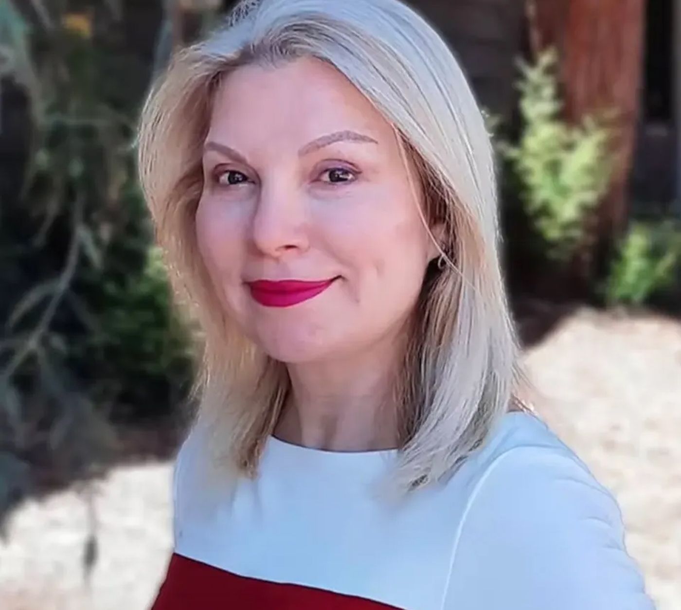 Woman with blonde hair and pink lipstick.