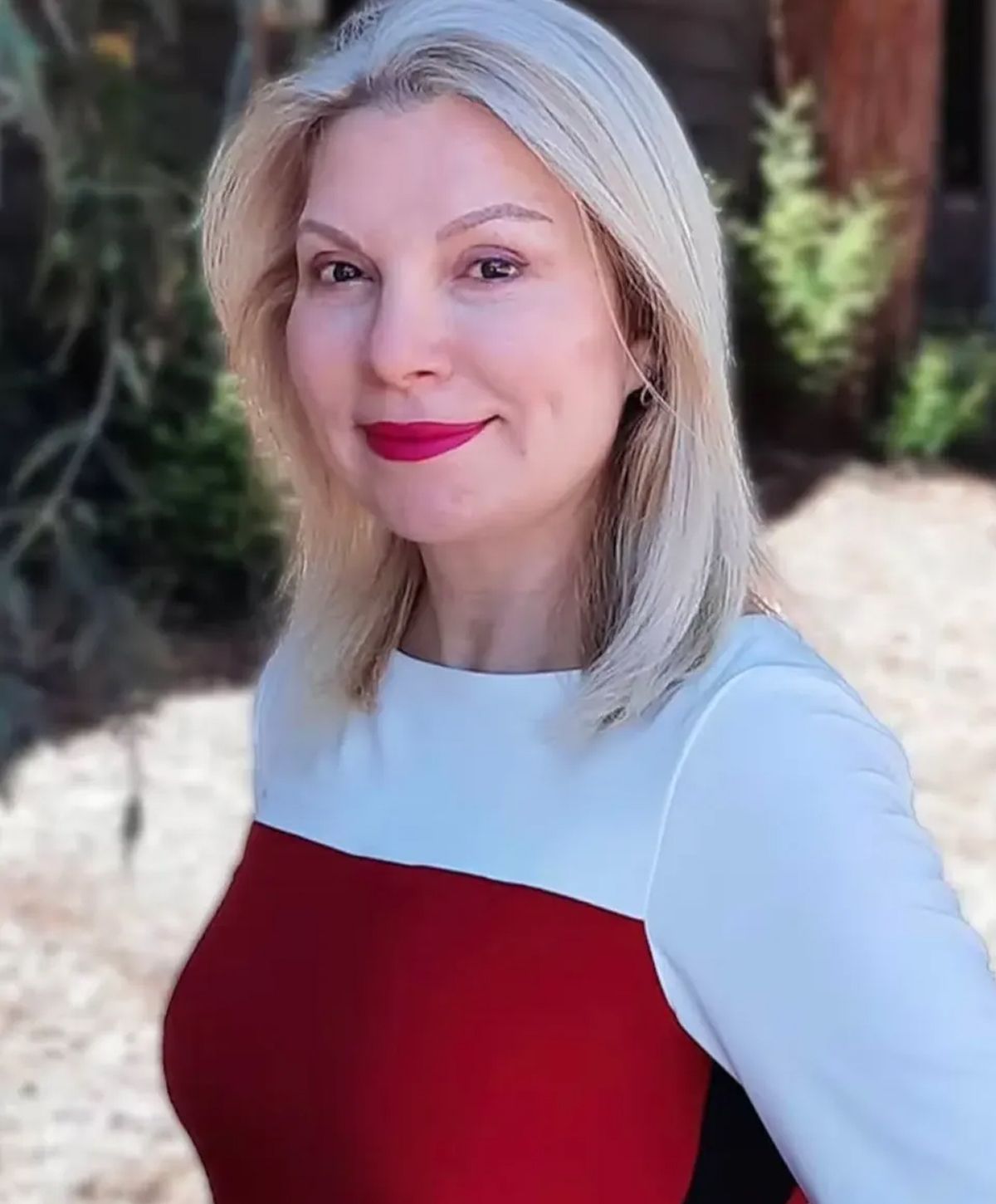 Woman smiling with blonde hair and red lipstick.