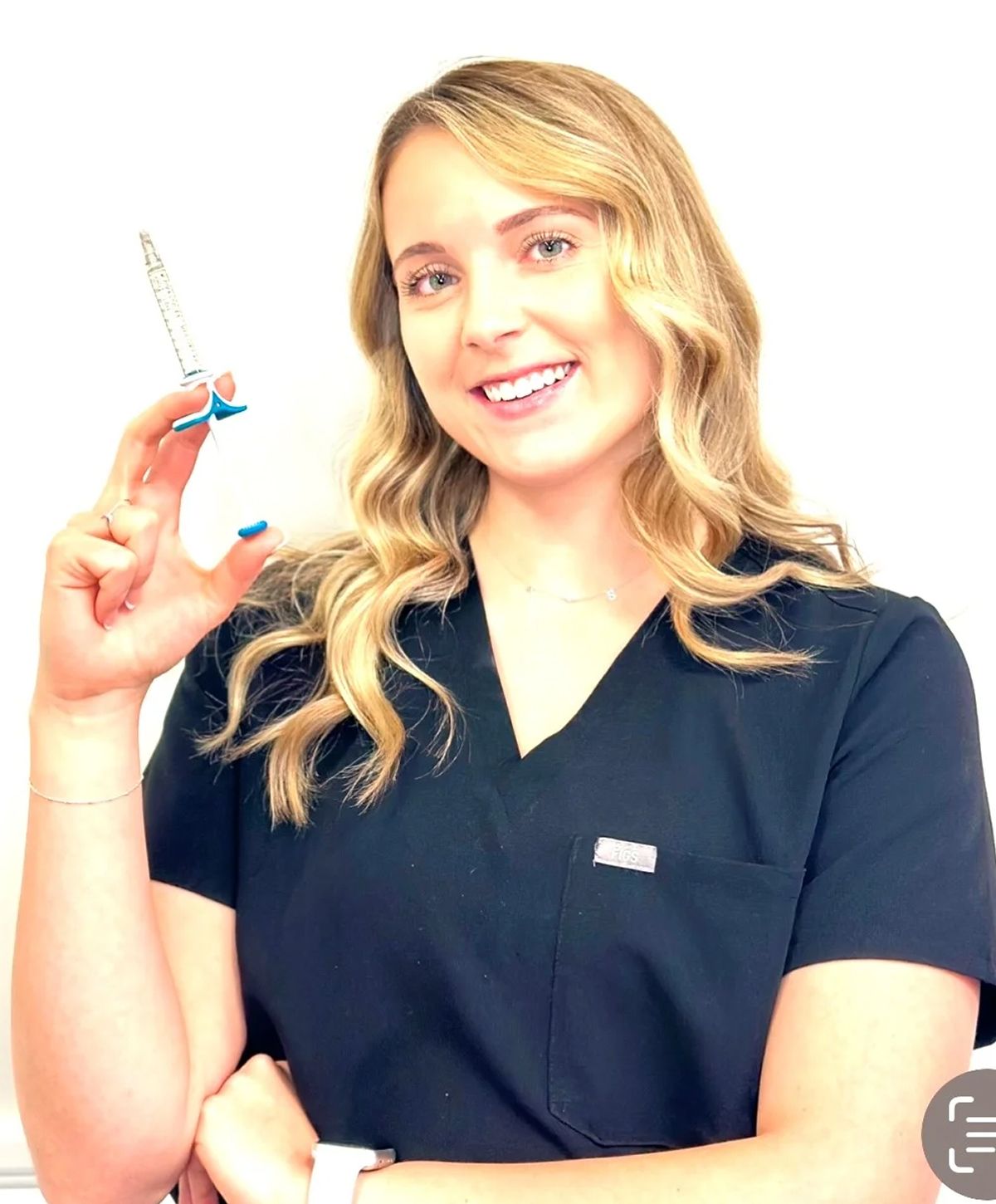 Healthcare professional holding a syringe and smiling.