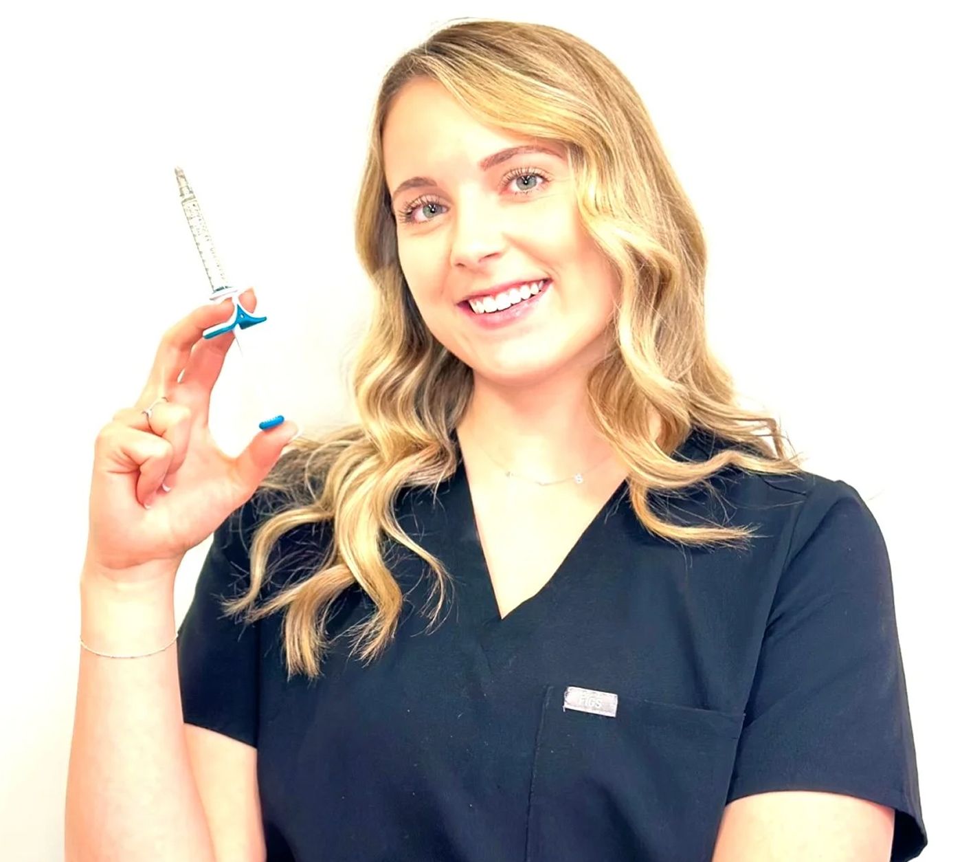 Healthcare professional holding a syringe, smiling.