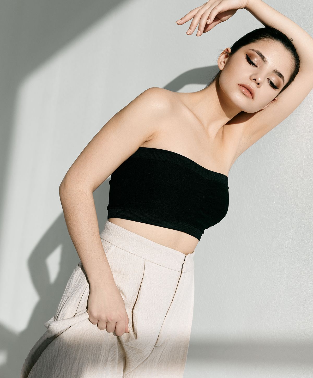 Model posing in stylish outfit against a wall.