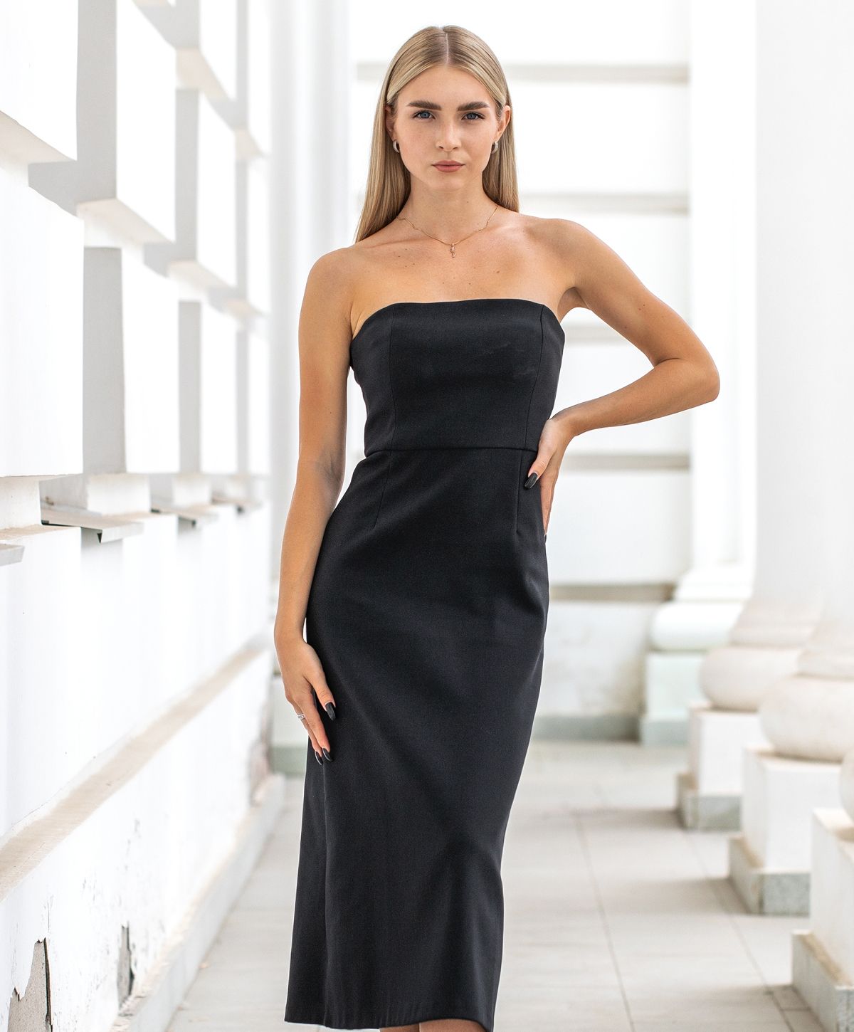 Model in a strapless black dress posing confidently.