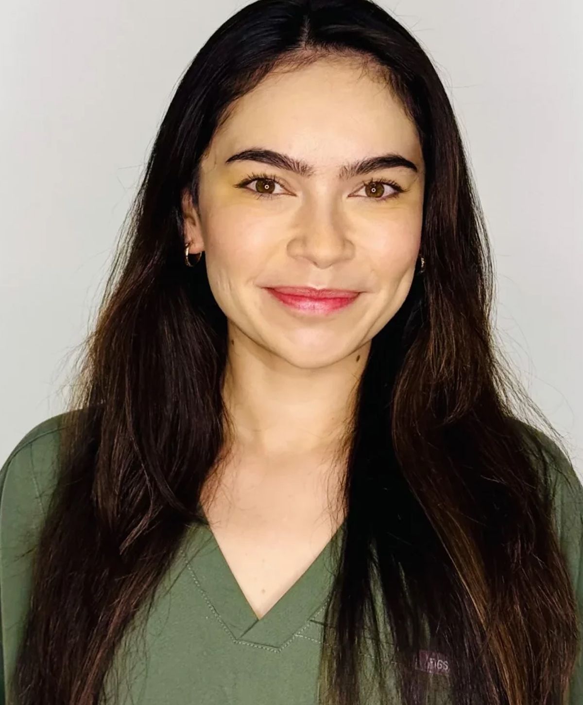 Smiling woman in a green top with long hair.