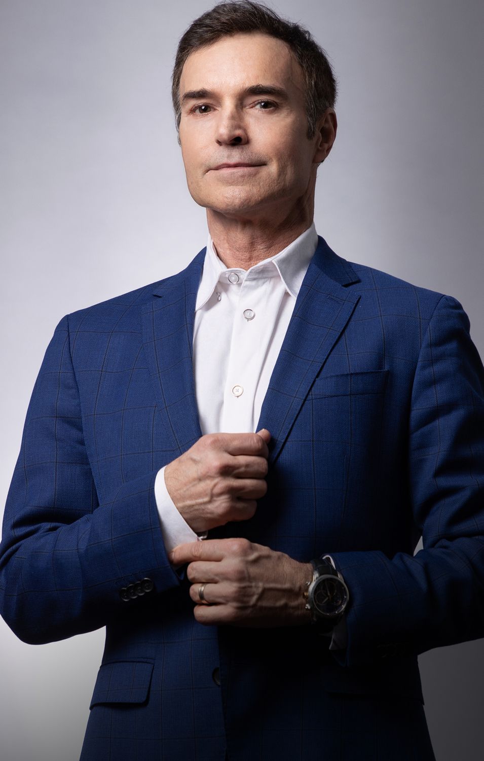 Man adjusting his blazer in studio lighting.