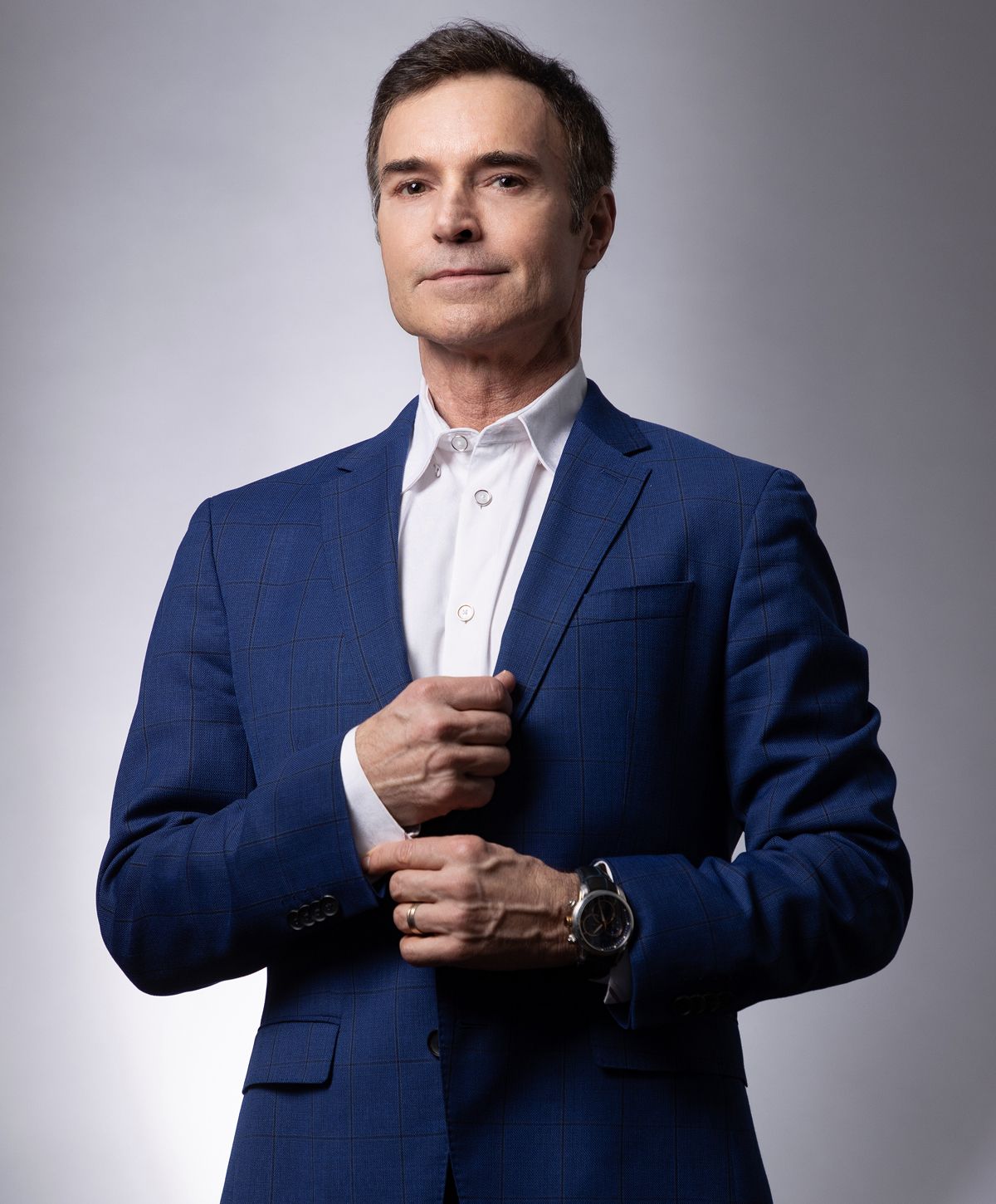 Man in blue suit adjusting his jacket.