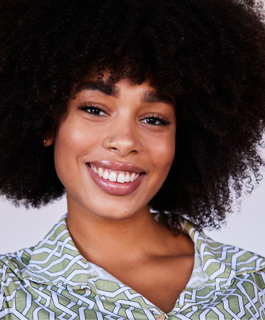 Smiling person with curly hair and patterned shirt.