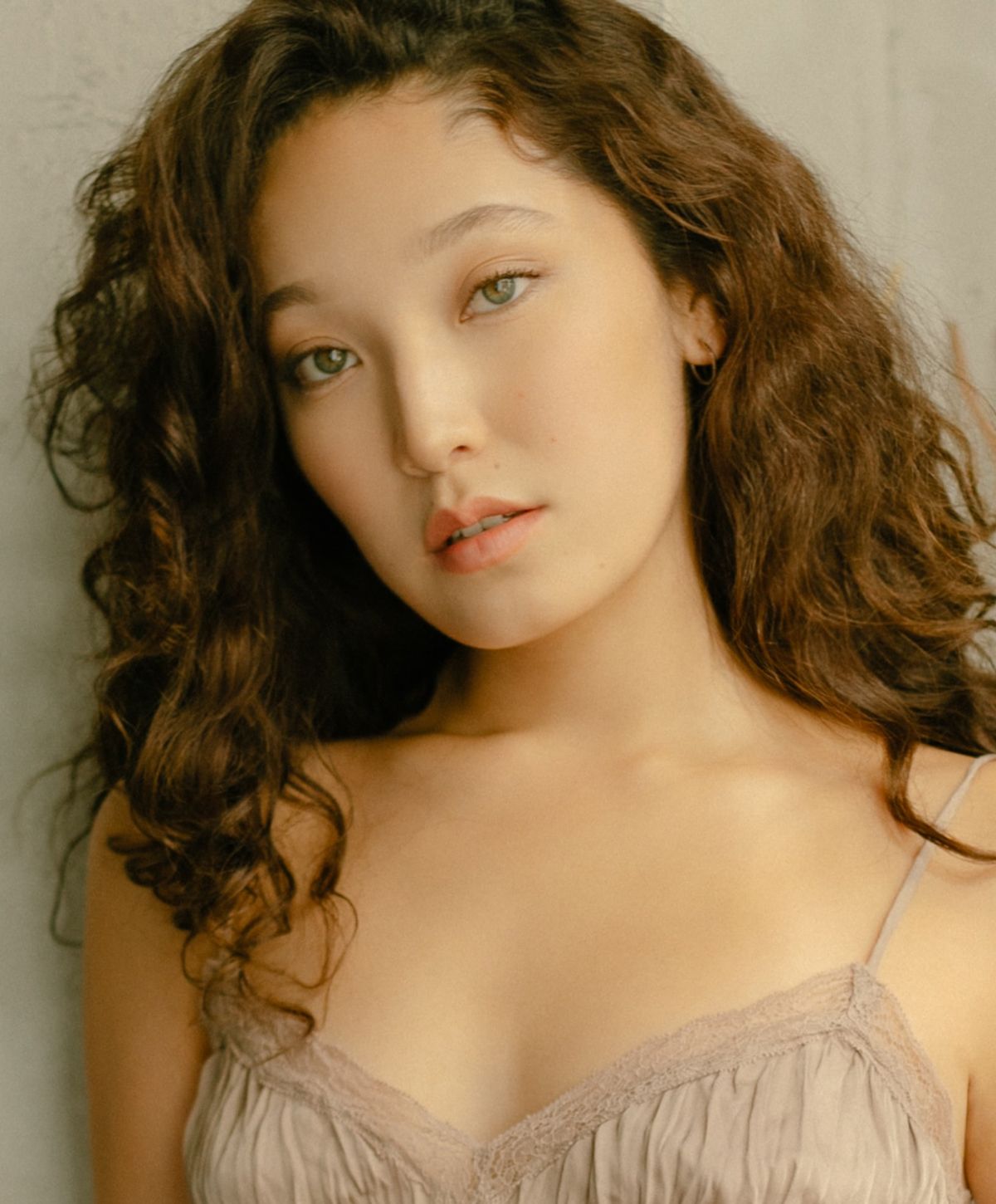 Woman with curly hair and striking green eyes.