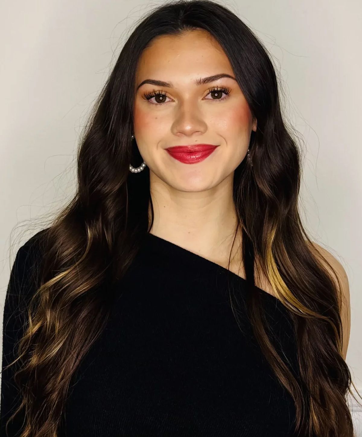 Woman with long hair and red lipstick smiling.