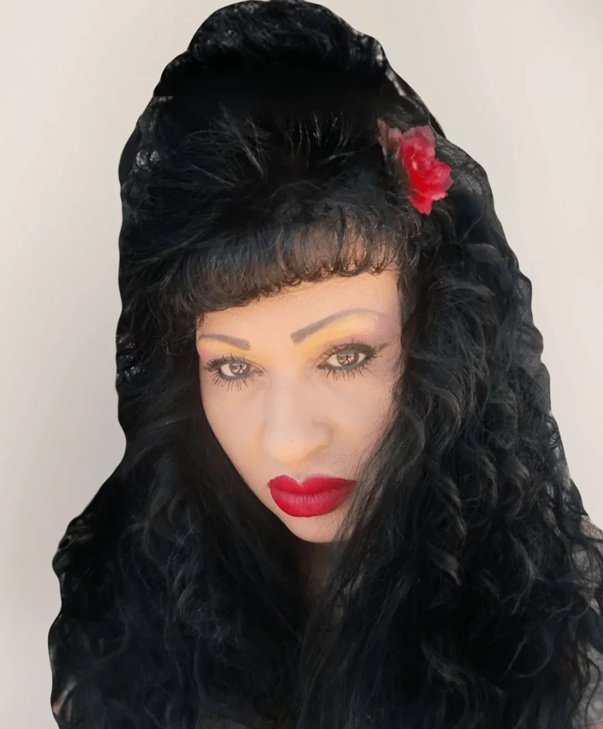 Woman with curly hair and bold red lips.