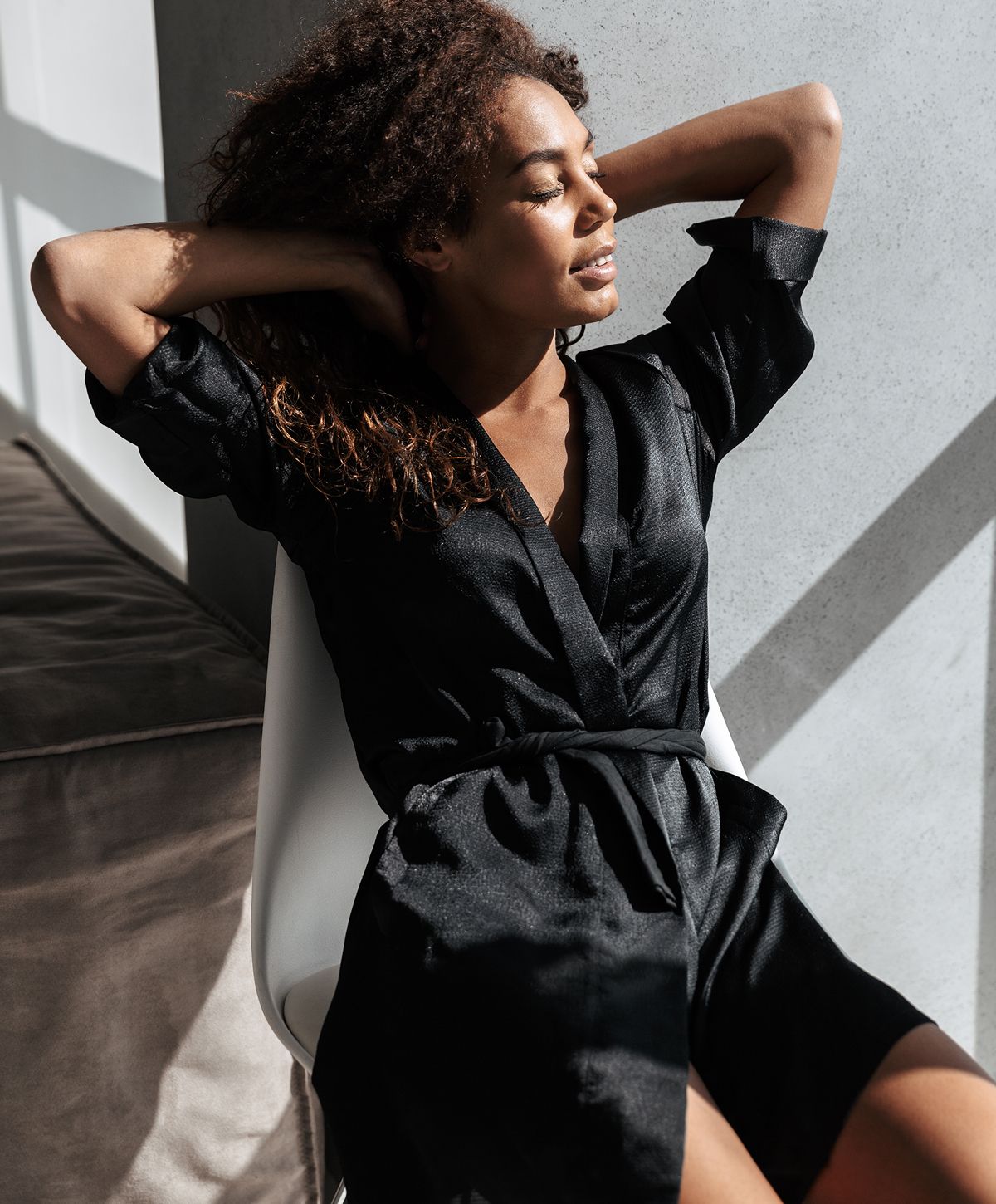 Woman in black robe enjoying sunlight indoors