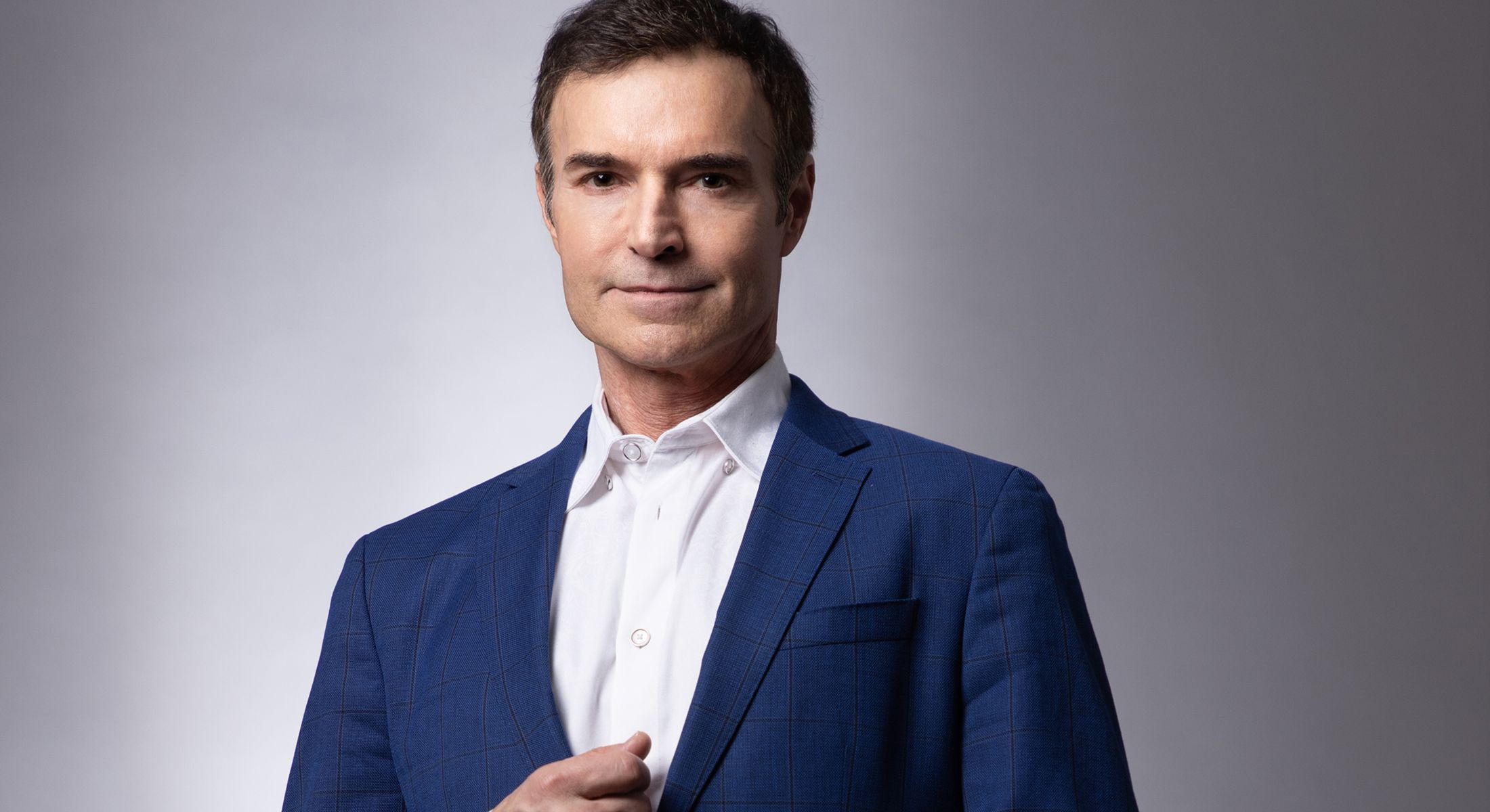 Man in blue suit against neutral background.