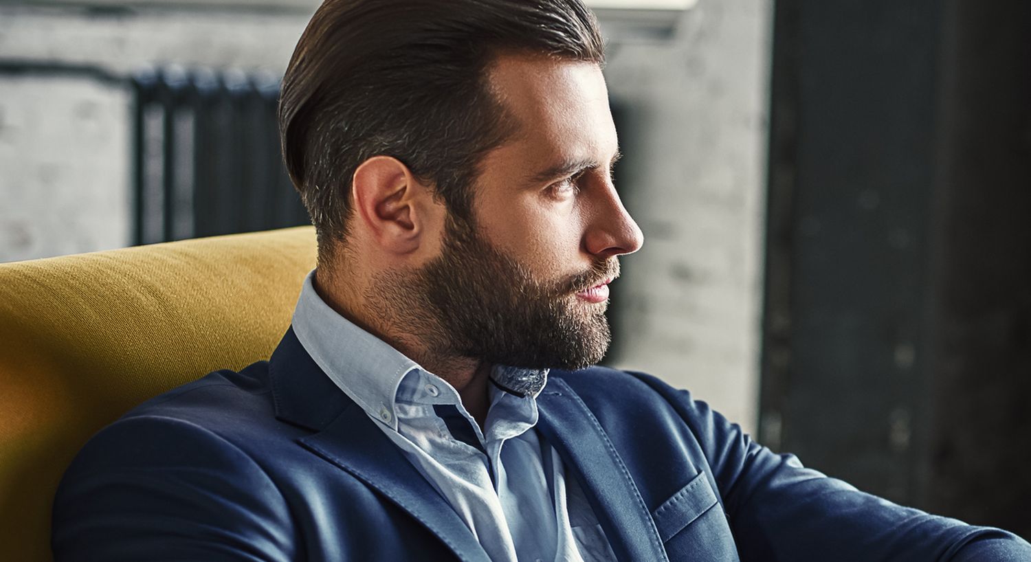 Man in suit sitting on a yellow chair.