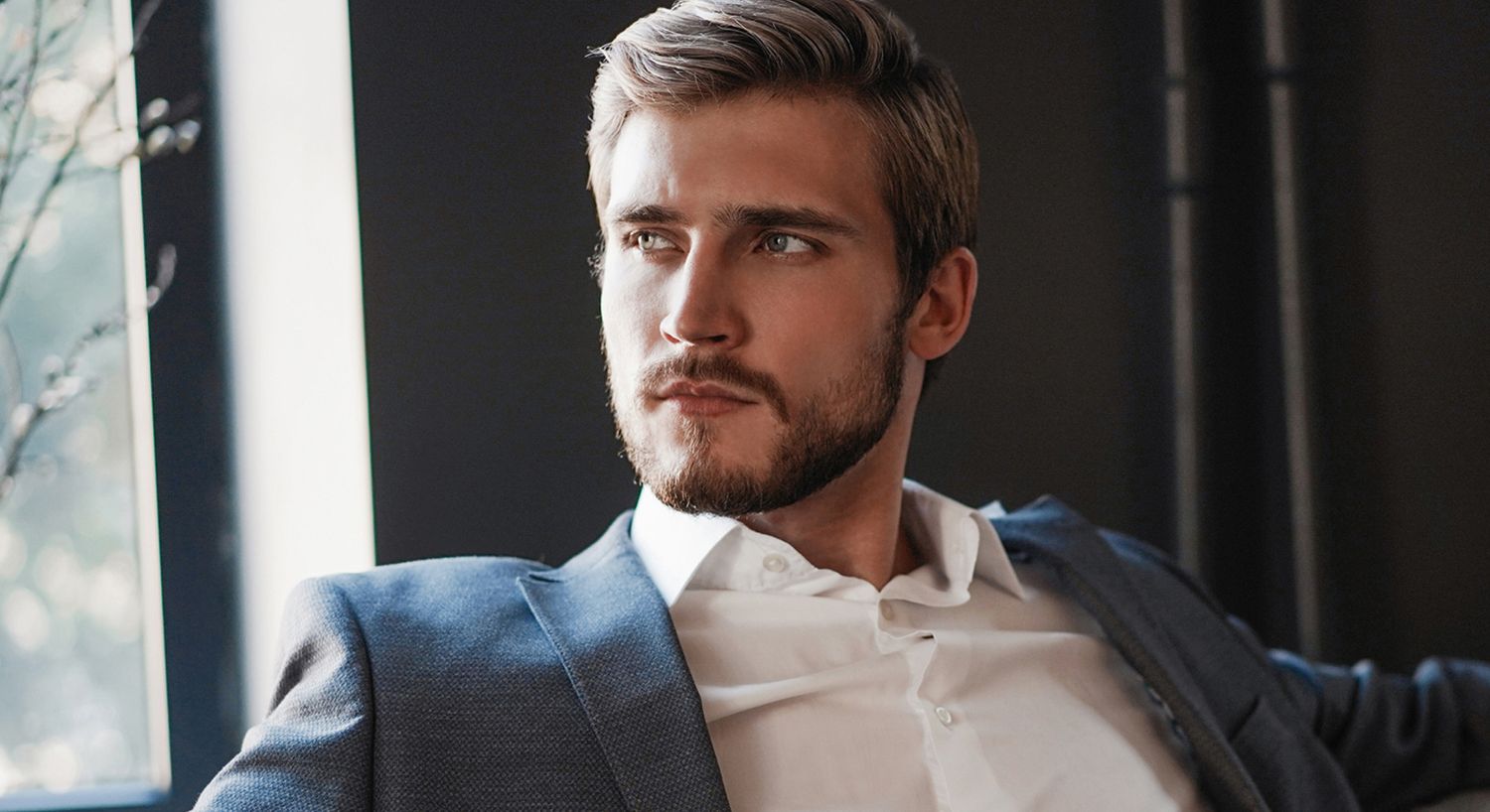 Man in suit looking thoughtfully out a window.
