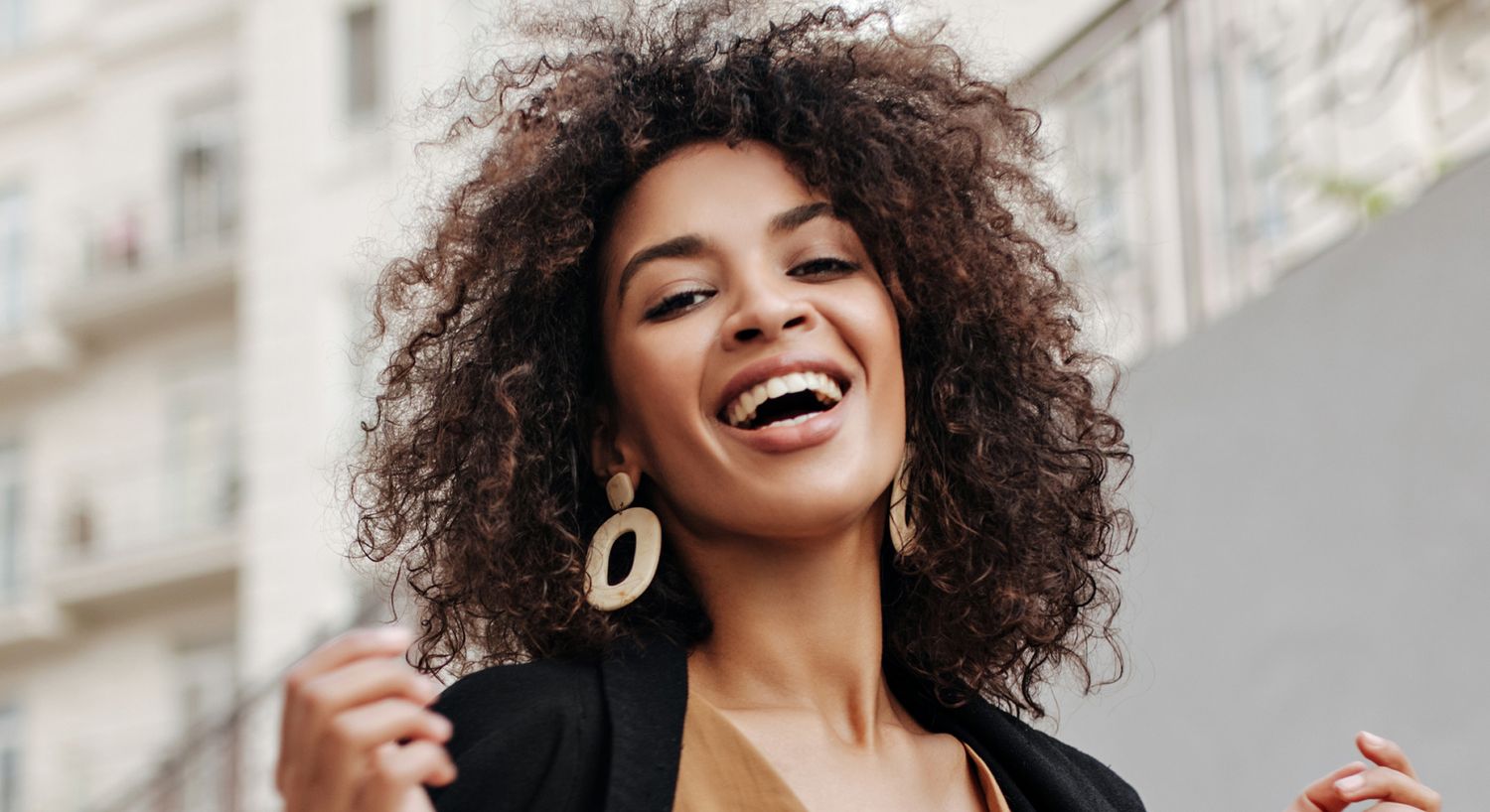 Smiling woman with curly hair and earrings.