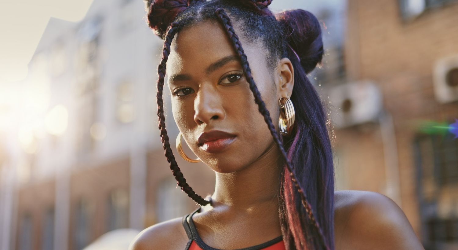 Young woman with braided hair and earrings.