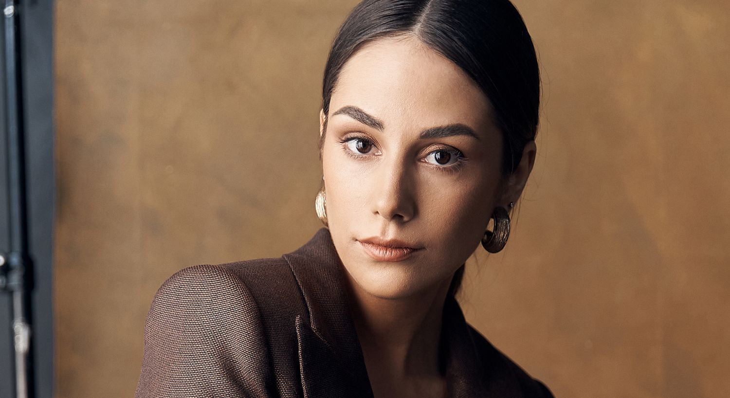 Woman with dark hair and statement earrings.