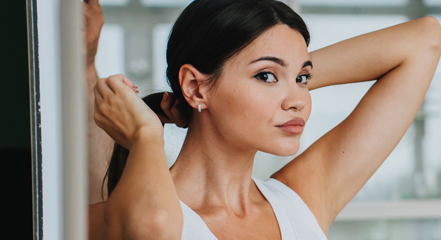 Woman styling her hair in front of a mirror.